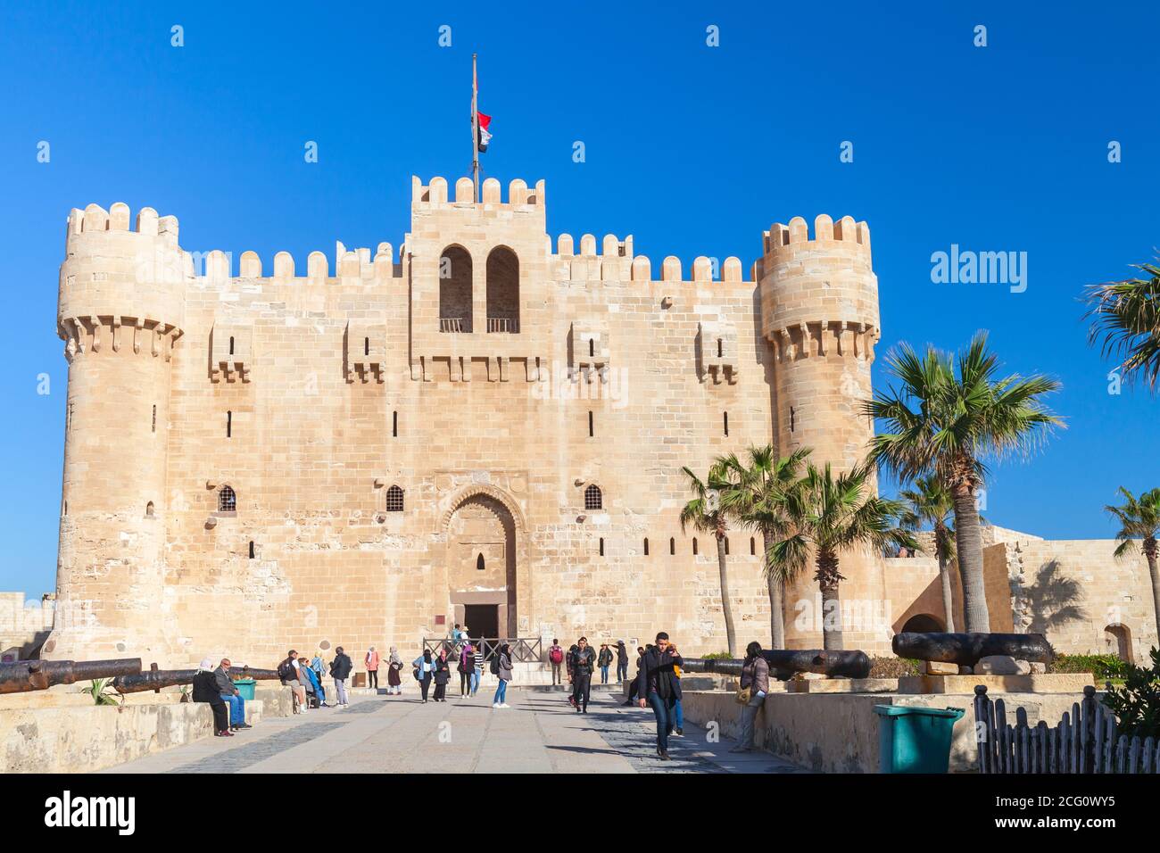 Alexandria, Egypt - December 14, 2018: People walk near The Citadel of Qaitbay or the Fort of Qaitbay. It is a 15th-century defensive fortress located Stock Photo