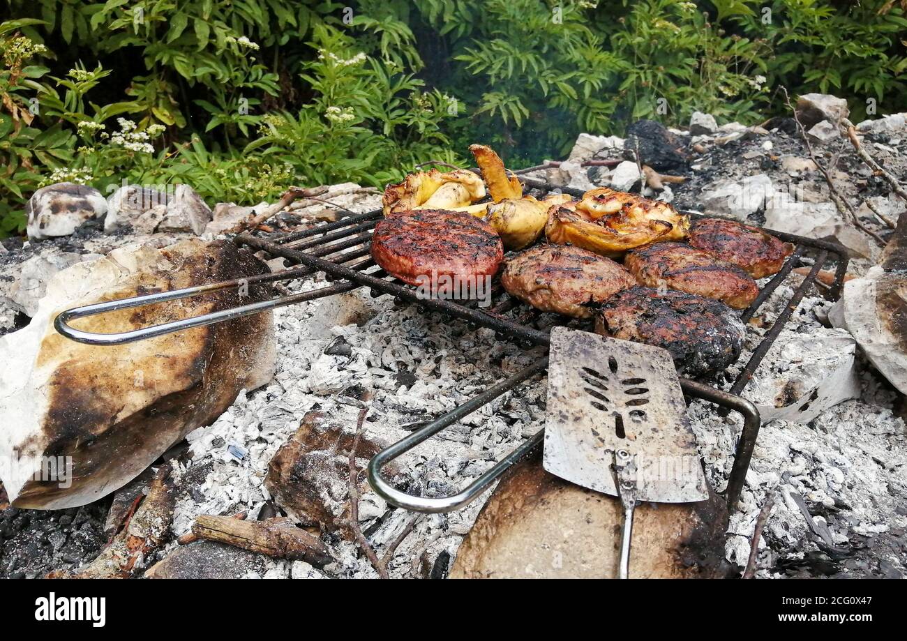 Mixed grilled meat with chicken and hamburger in real life outdoor barbecue fire Stock Photo