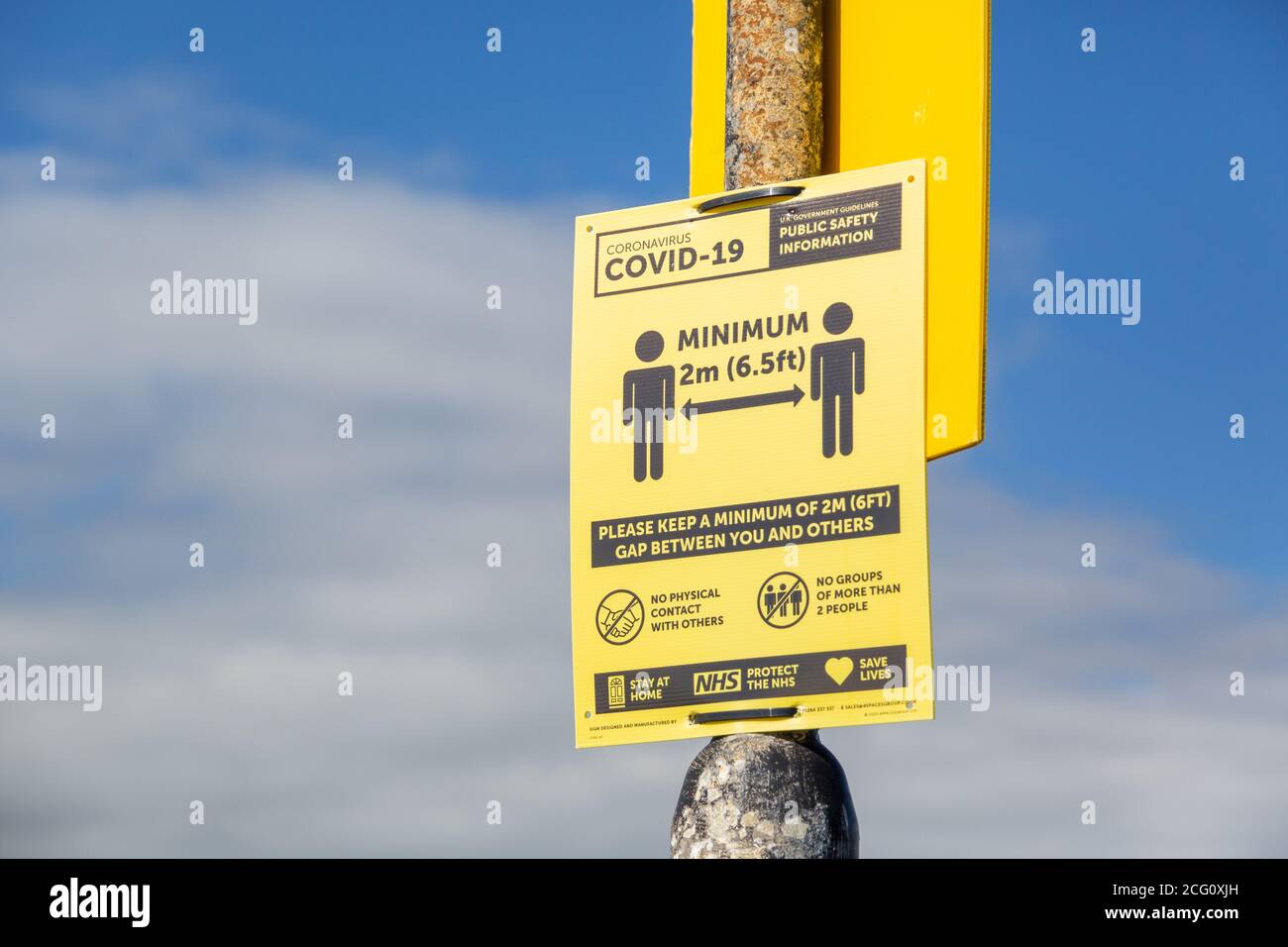 A sign stating the current social distancing guidelines on a lamppost, suggesting keeping two meters apart during the coronavirus pandemic Stock Photo