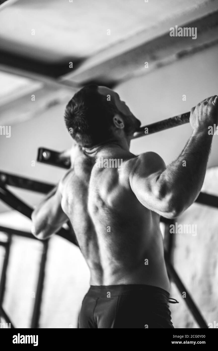 Fitness toes to bar man pull-ups bars workout exercise at gym bw Stock Photo
