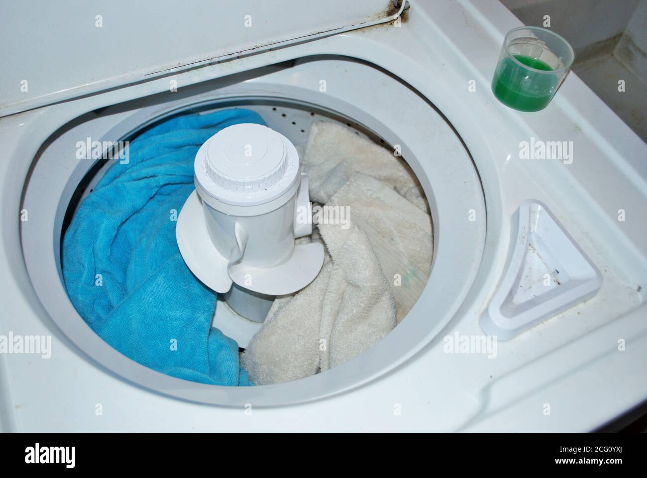 load of dirty towels in a washing machine with laundry detergent Stock