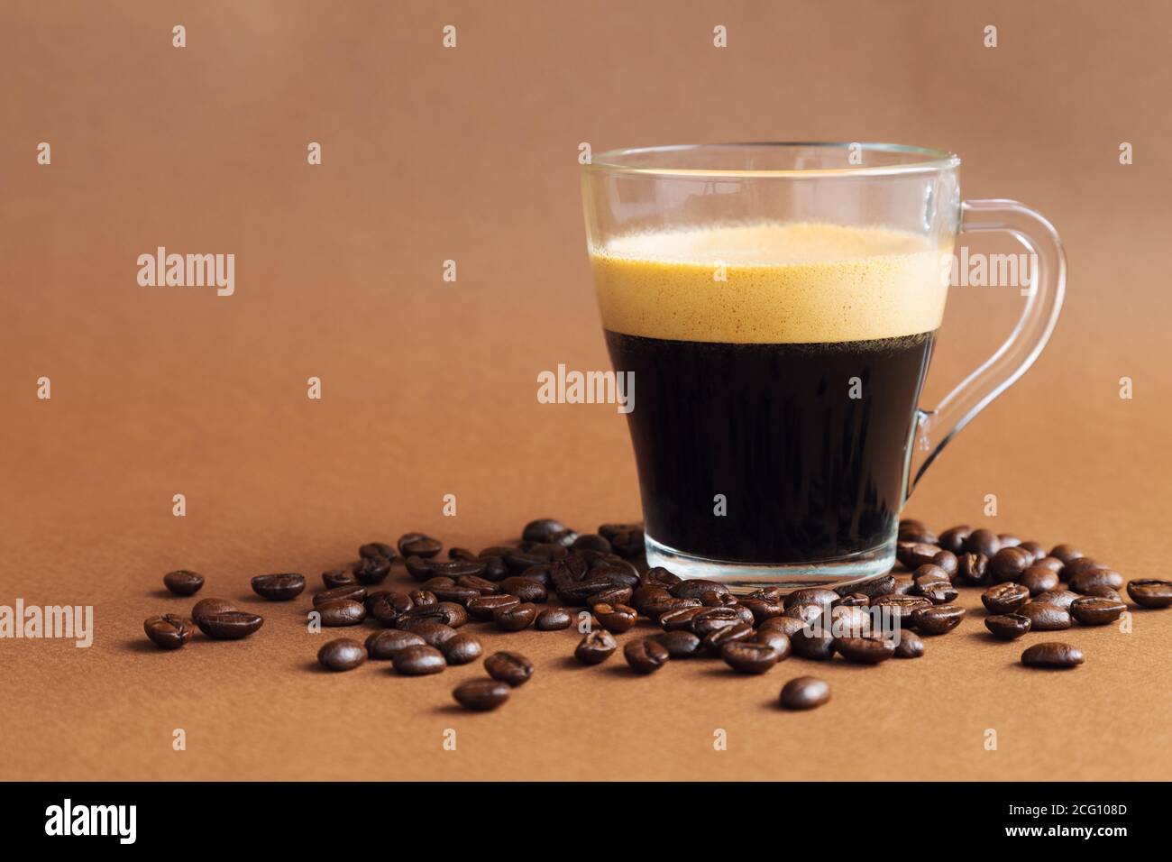 Cup with espresso coffee on brown background with coffee beans. Minimalist monochrome design. Stock Photo
