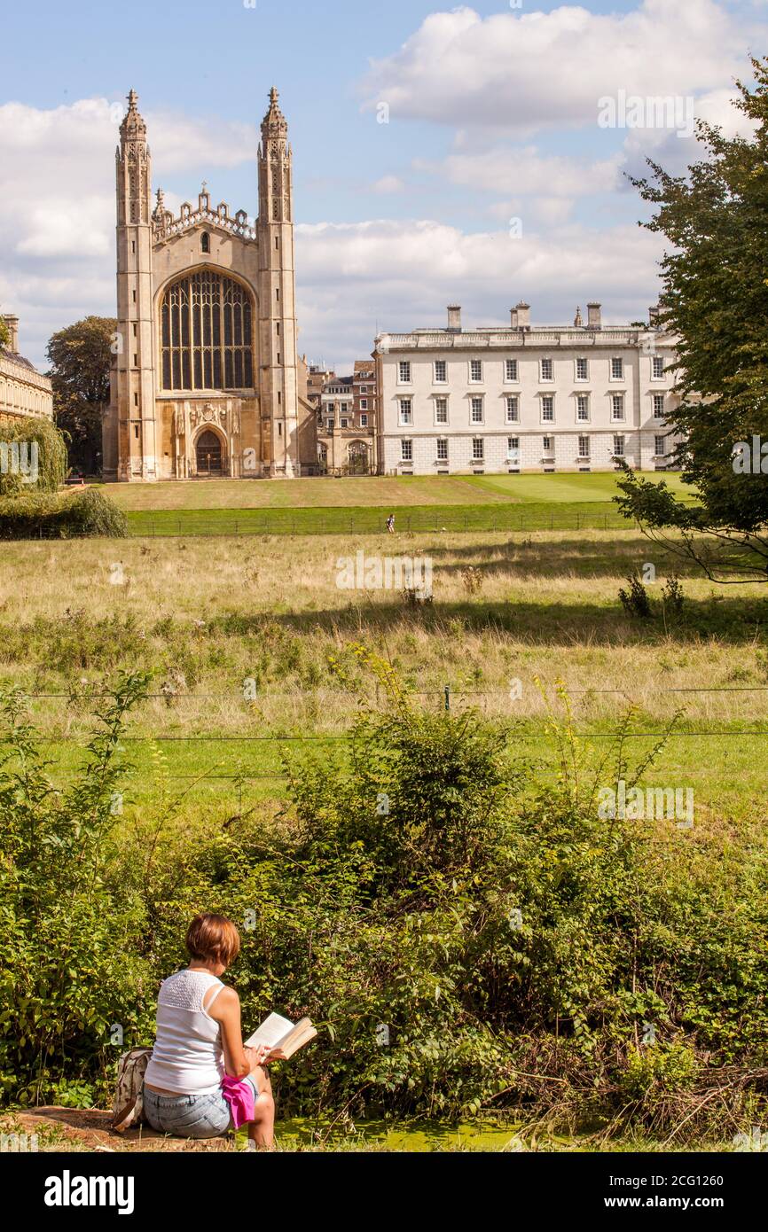 Woman sitting reading a book overlooking the backs and the meadows leading to kings collage Cambridge Cambridgeshire Stock Photo