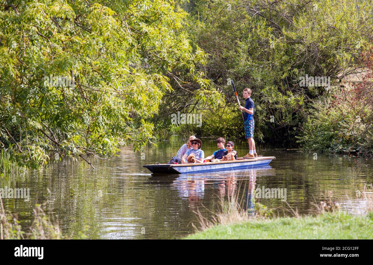 People children and families enjoying summer sunshine punting on the river Cam in Grantchester Meadows  Cambridge Cambridgeshire Stock Photo
