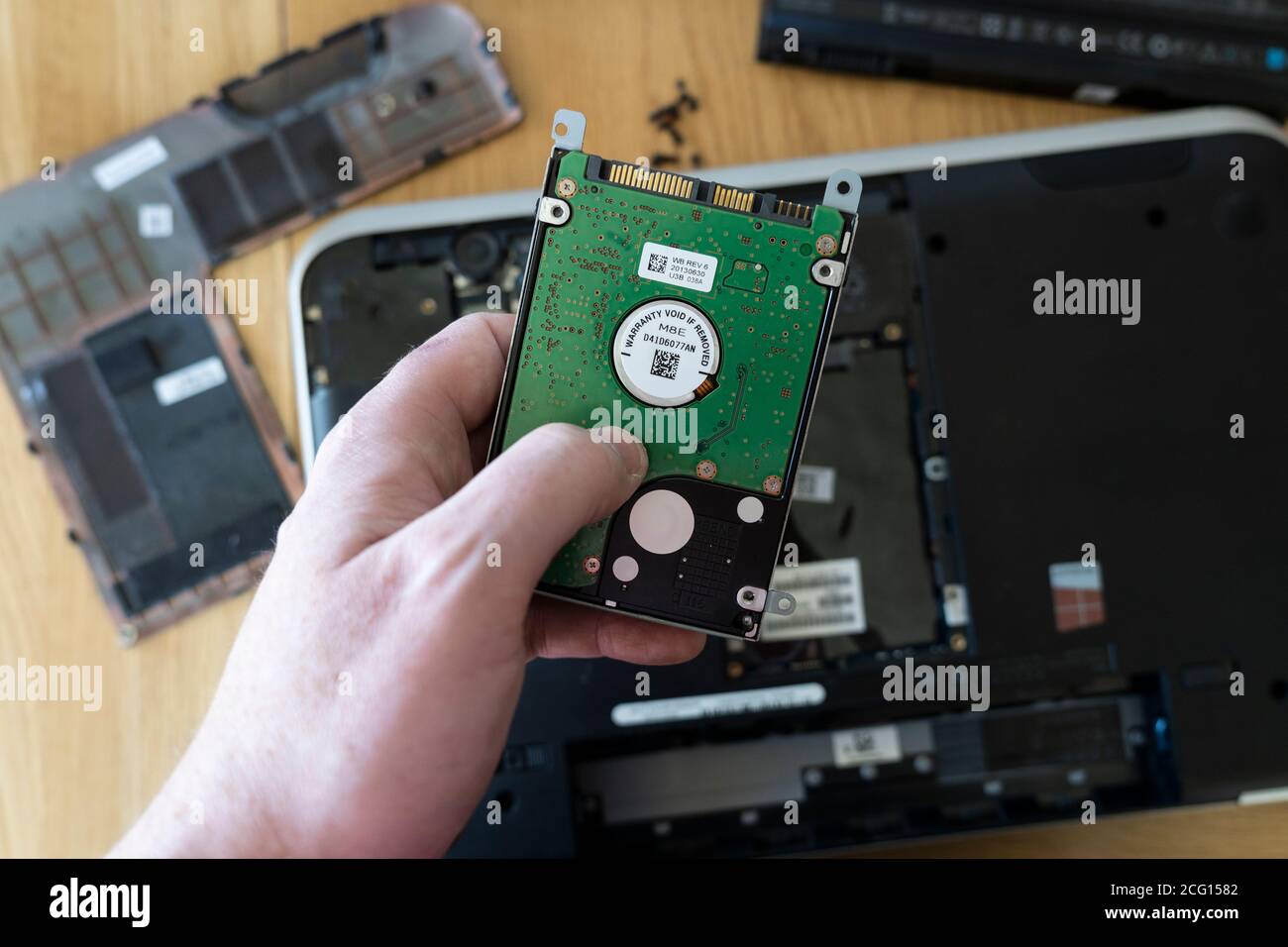 Man's hand holding a Seagate 2.5' hard disk drive (HDD) removed from a laptop. Theme: data storage, computer repair, old technology superseded, memory Stock Photo