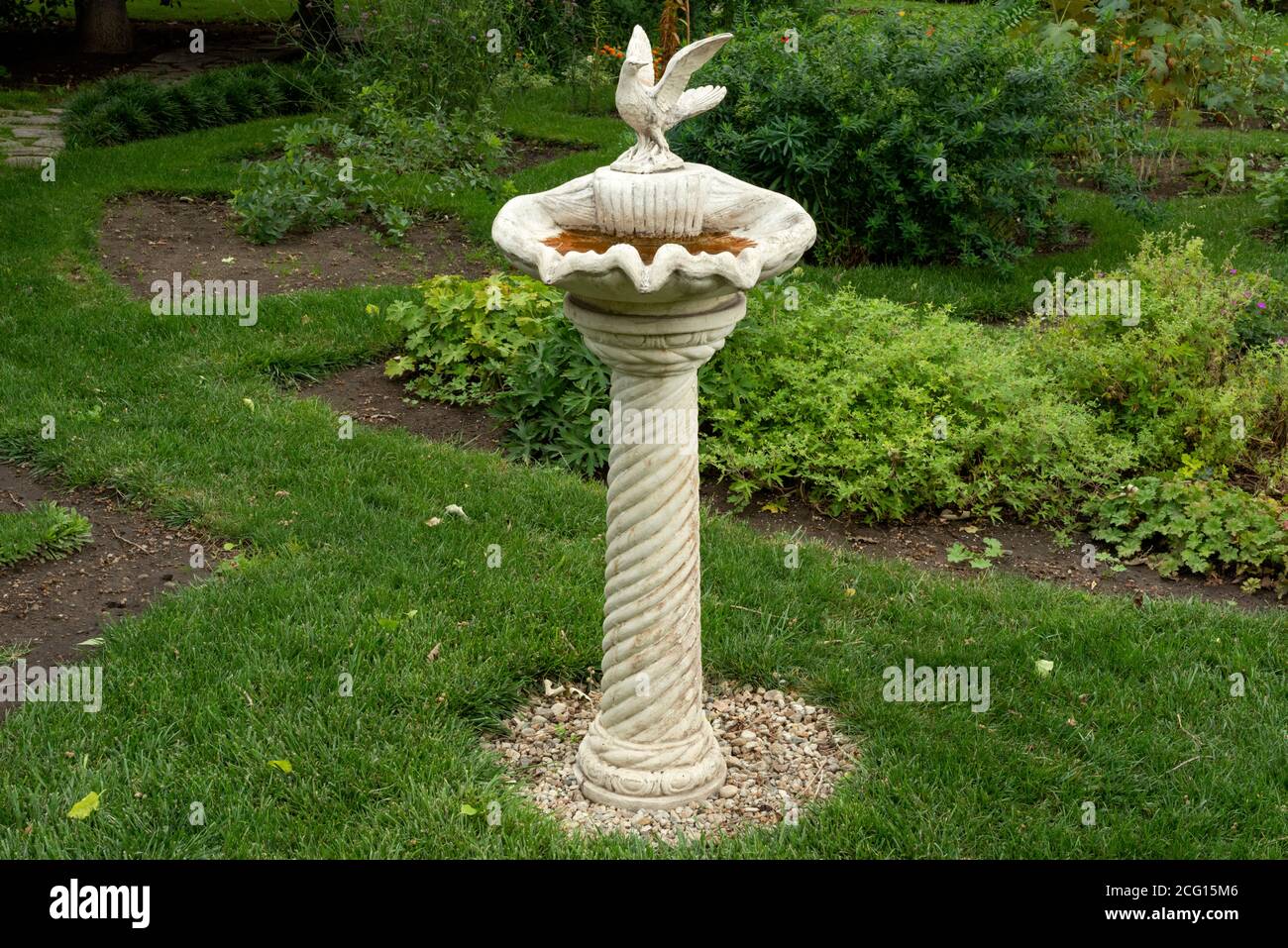 Unique and antique ornamental tall cast stone concrete bird bath or birdbath and water fountain with pigeon figurine as garden decoration Stock Photo