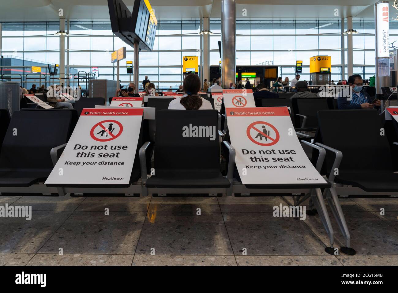 Seating blocked off with signs to maintain social distancing for public health, Terminal 3 in Heathrow Airport, for the Covid-19 Coronavirus pandemic Stock Photo