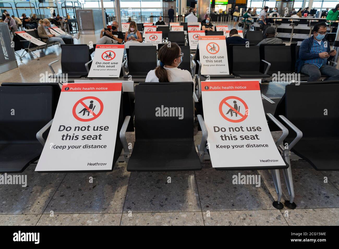 Seating blocked off with signs to maintain social distancing for public health, Terminal 3 in Heathrow Airport, for the Covid-19 Coronavirus pandemic Stock Photo
