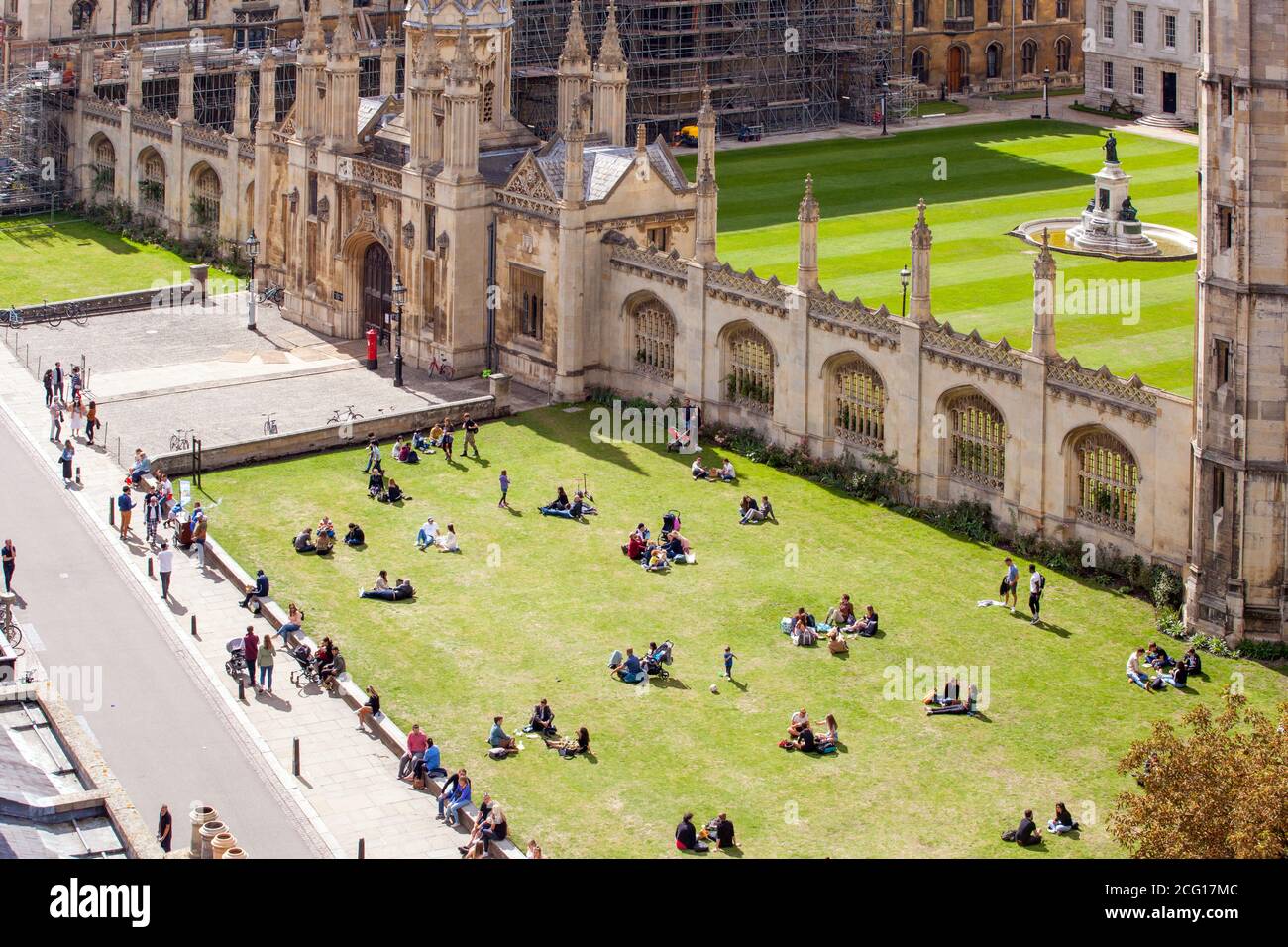 Tourists holidaymakers visitors and day trippers picnicking on the grass lawns in front of Kings collage Cambridge Cambridgeshire viewed from above Stock Photo