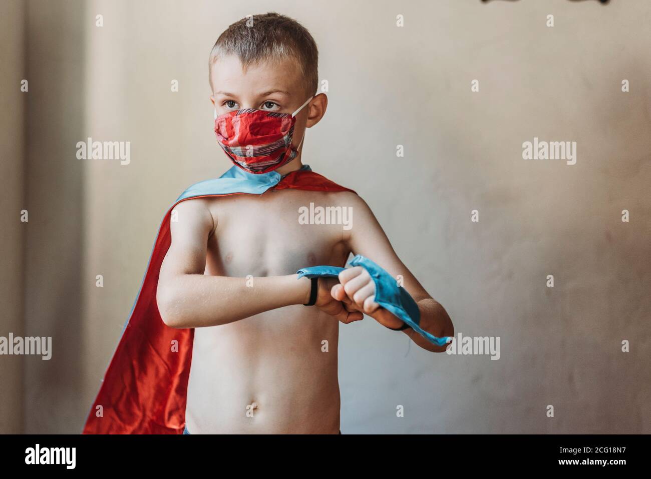 School age young boy dressed as super hero with face mask on at home Stock Photo