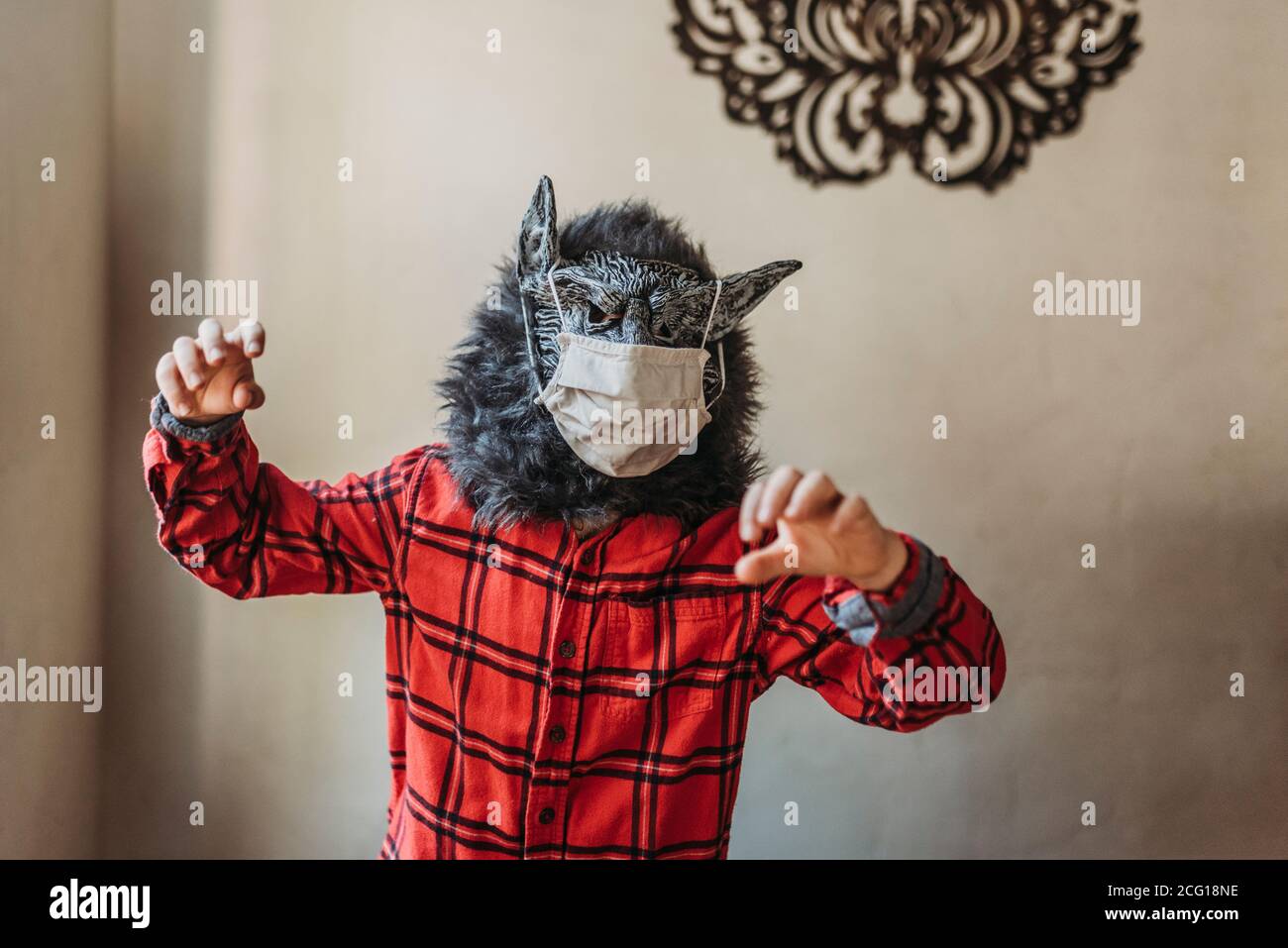 Young boy in wolf mask with face covering over mask standing at home