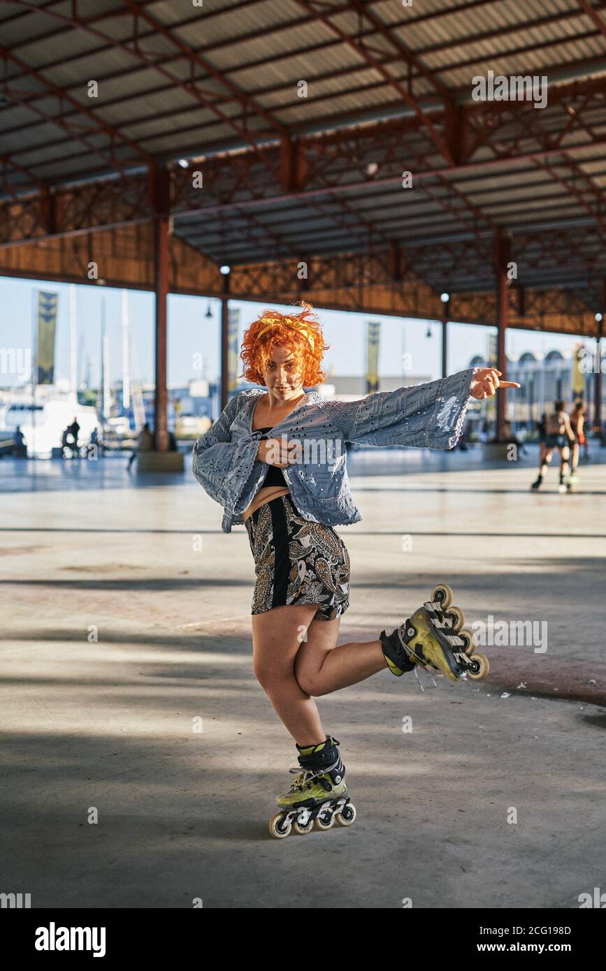 Young alternative redhead dancing in roller skates inside a hangar