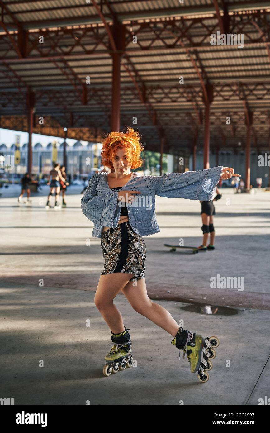 Young alternative redhead dancing in roller skates inside a hangar