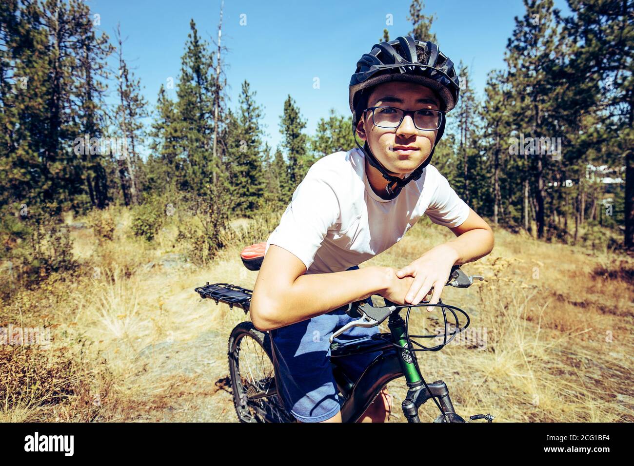 A teen boy takes a break frm riding on trails in north Idaho. Stock Photo
