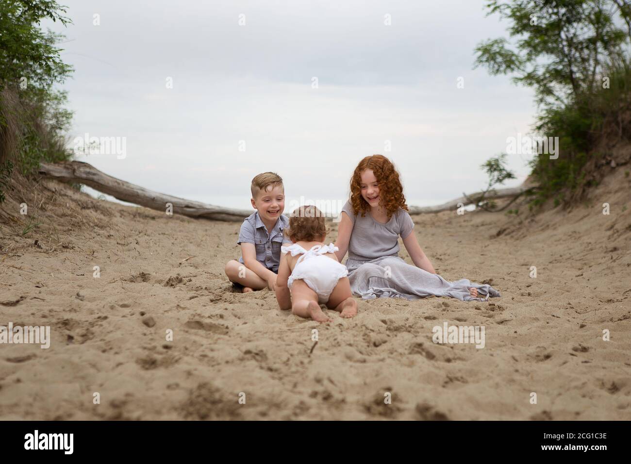 Three Siblings Playing on a Presque Isle Beach at Sunset Stock Photo