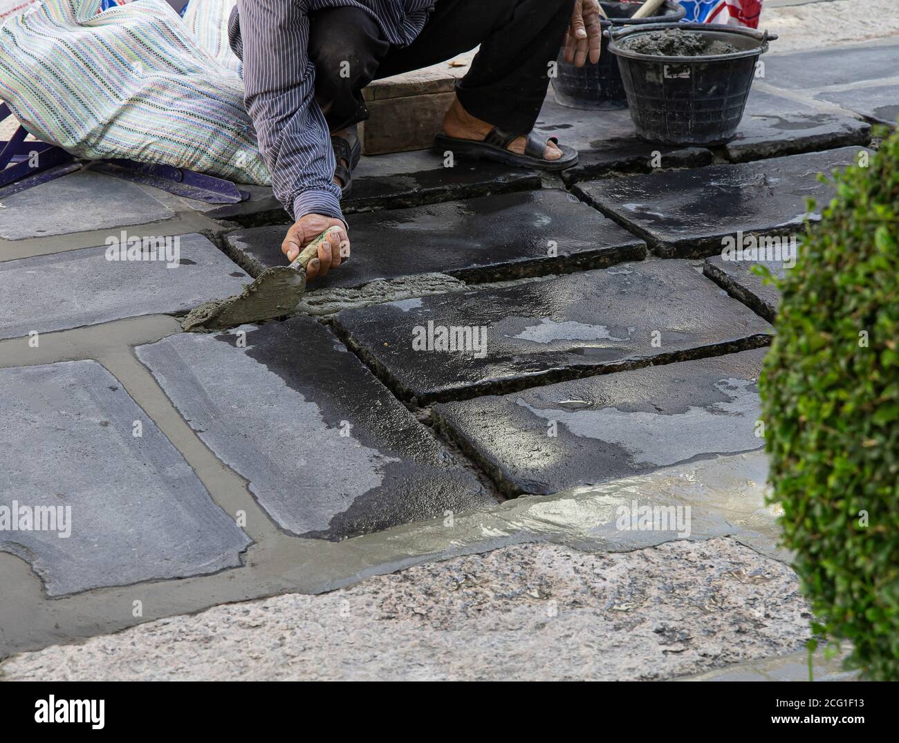 Construction workers are paving the sidewalk stone with cement. Stock Photo