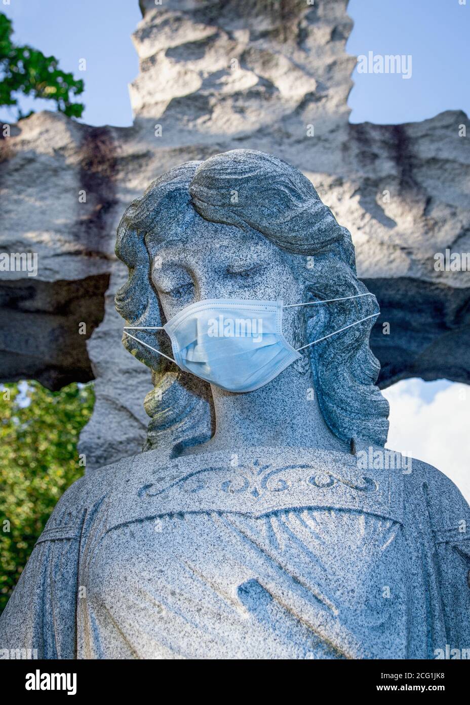 Close-up view of a cemetery angel statue wearing a surgical face-mask Stock Photo