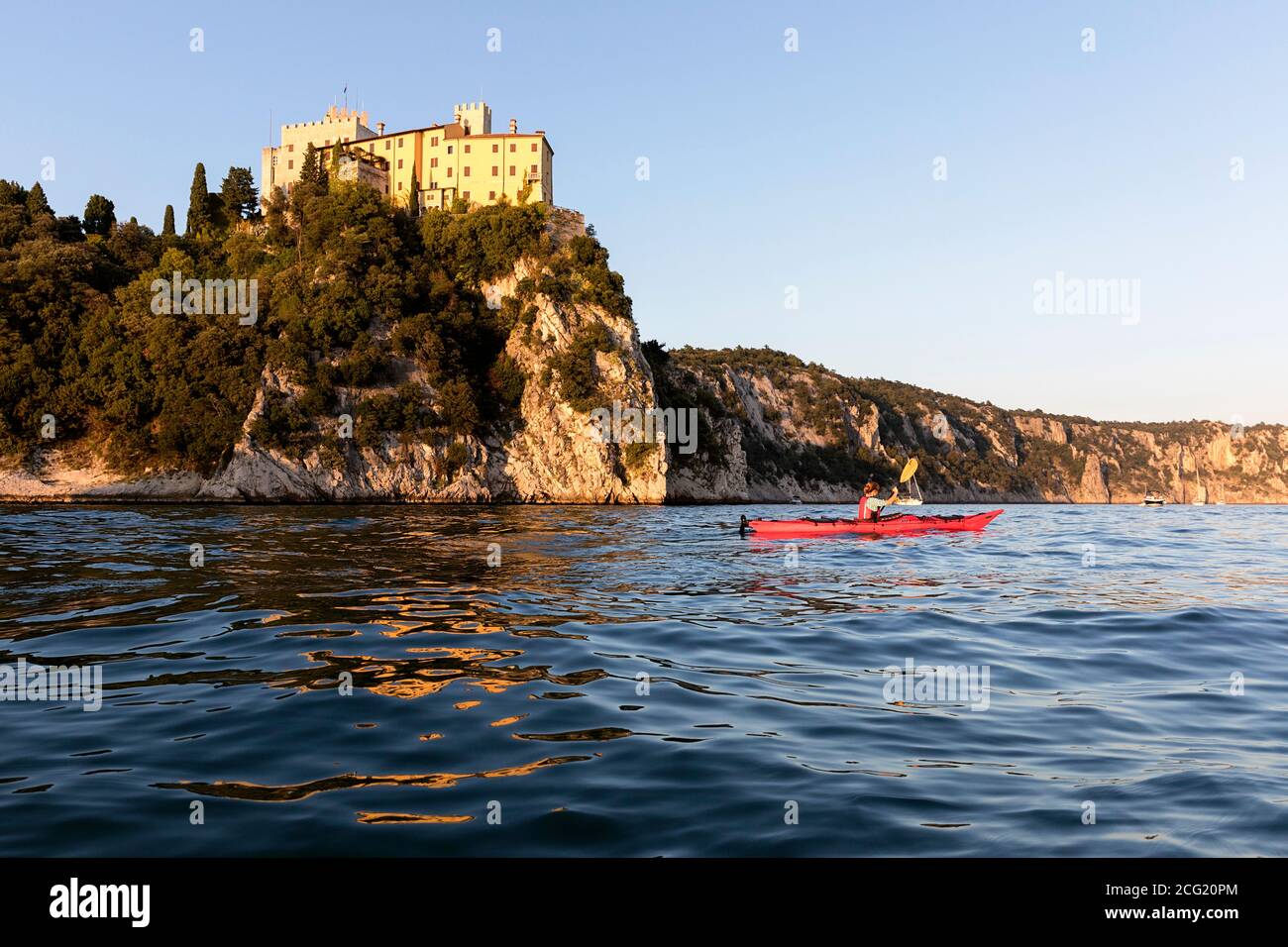 Woman in red kayak kayaking under the Duino Castle, Mediterranean, Trieste,  Italy Stock Photo - Alamy