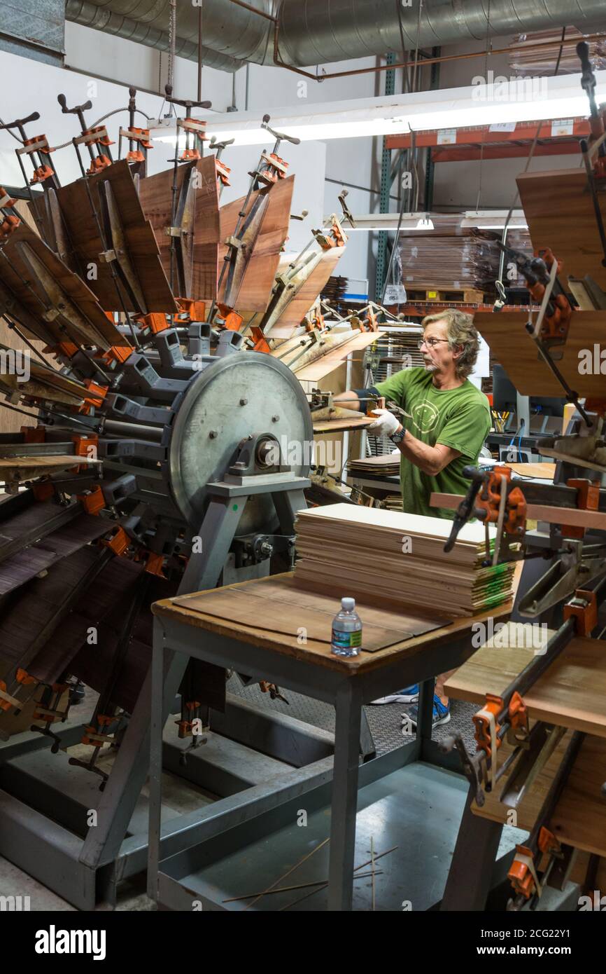 A worker glues the matched pieces of exotic wood for guitar backs together on a special clamping machine in the Taylor Guitar factory in El Cajon, Cal Stock Photo