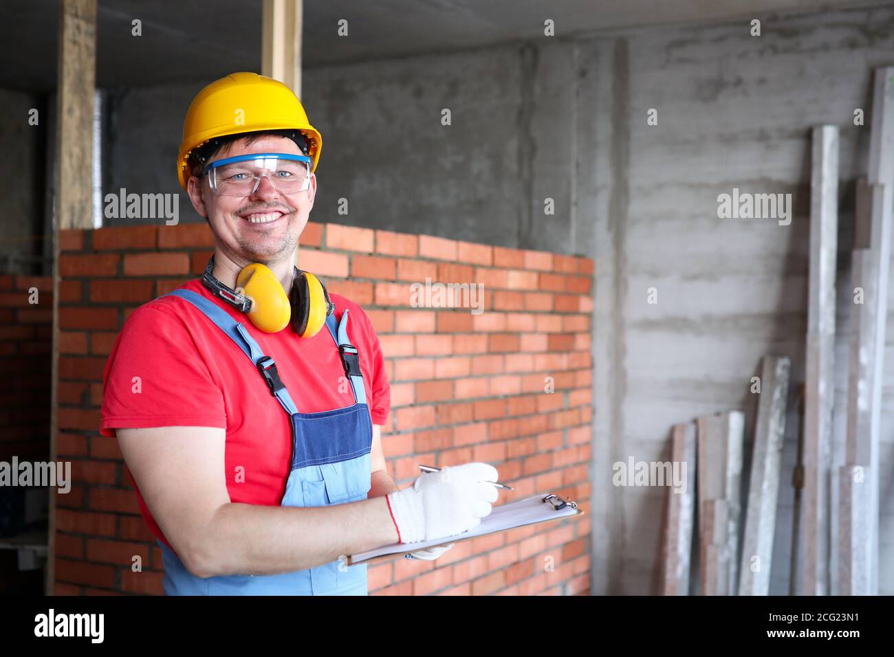 Smiling builder writing on clipboard work results Stock Photo