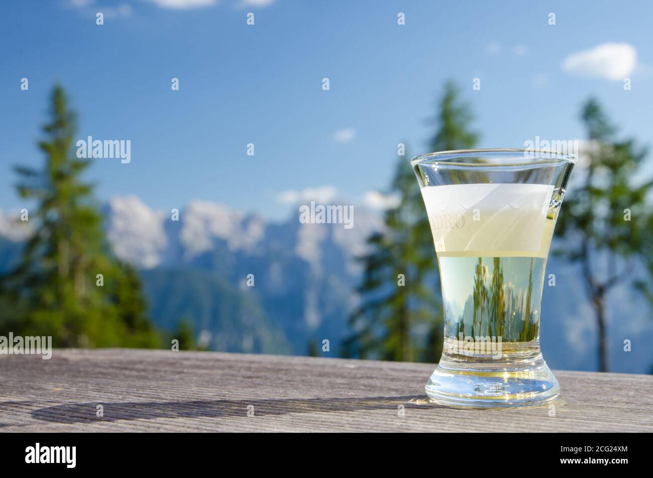 Dolomites, Italy. August 2020. Summer in the mountains. A glass of grappa with the Dolomites in the background on a sunny day Stock Photo