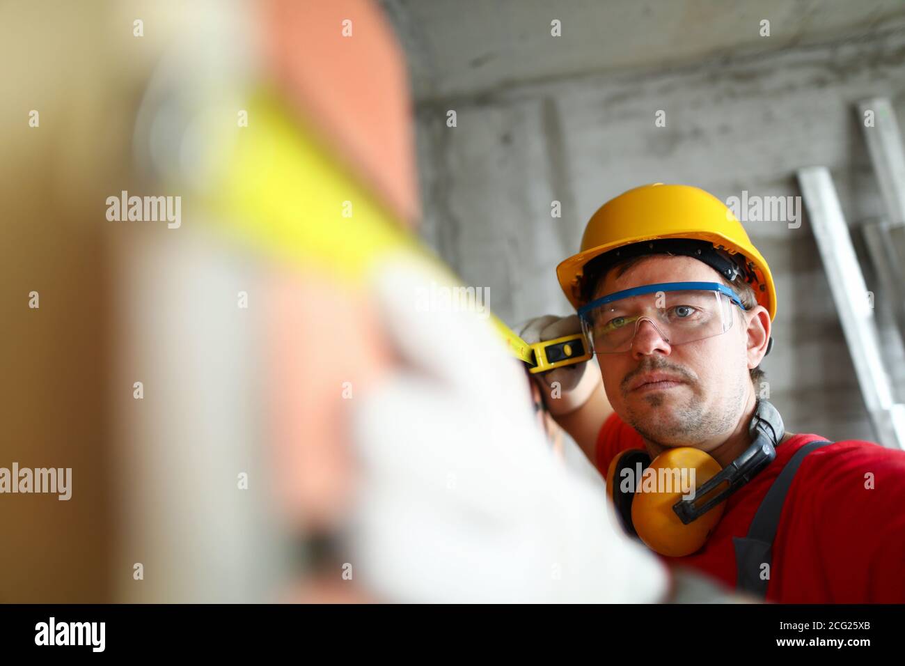 Builder measuring wall level with roulette tape Stock Photo