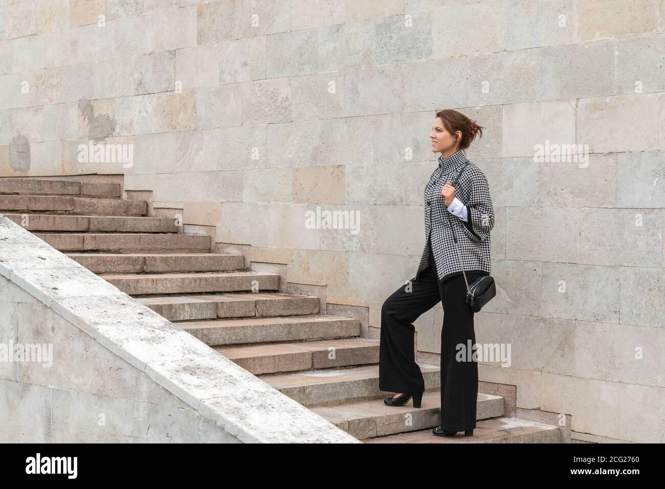 Businesswoman climbing up a concrete staircase on city wall background. Successful woman concept. Copy space Stock Photo