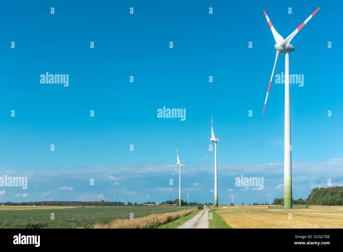 Wind turbines in agricultural fields on blue and cloudy sky background ...