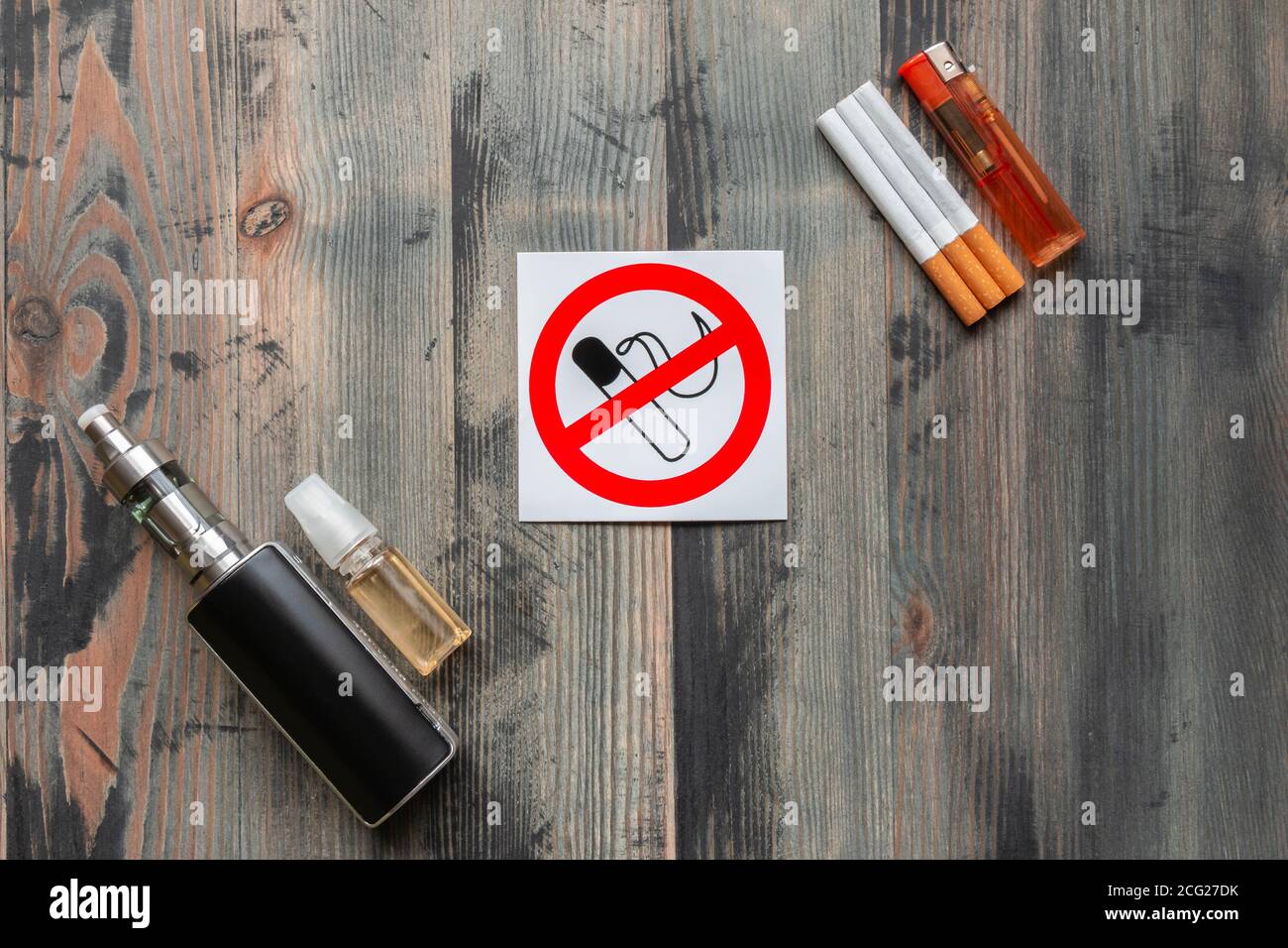 Black e-cigarette, sweet e-liquid, tobacco cigarettes with lighter and sign stop smoking on grey wooden background. Top view. Stop smoking concept Stock Photo