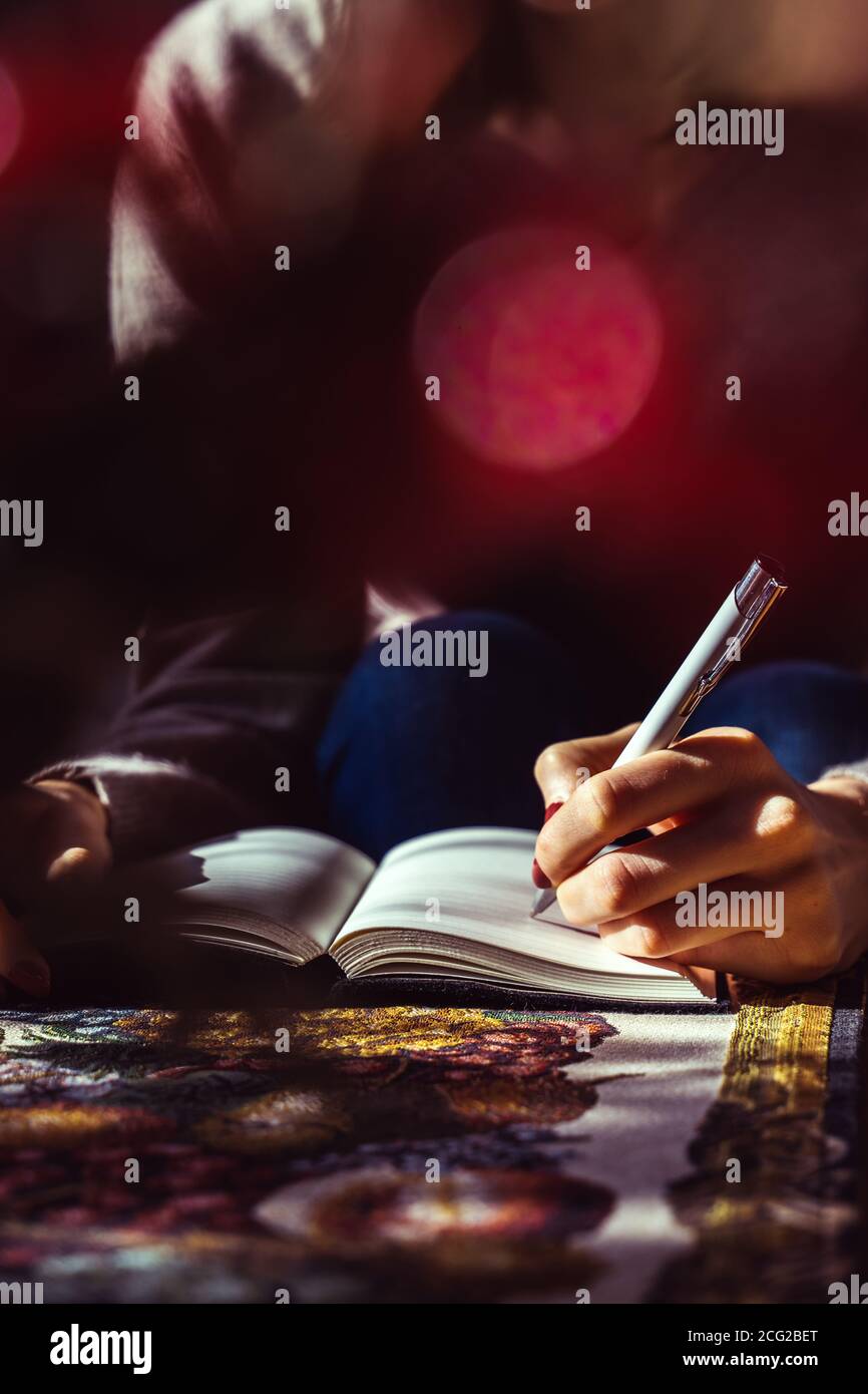 young woman writing to do list of goals. female student dreaming Stock Photo