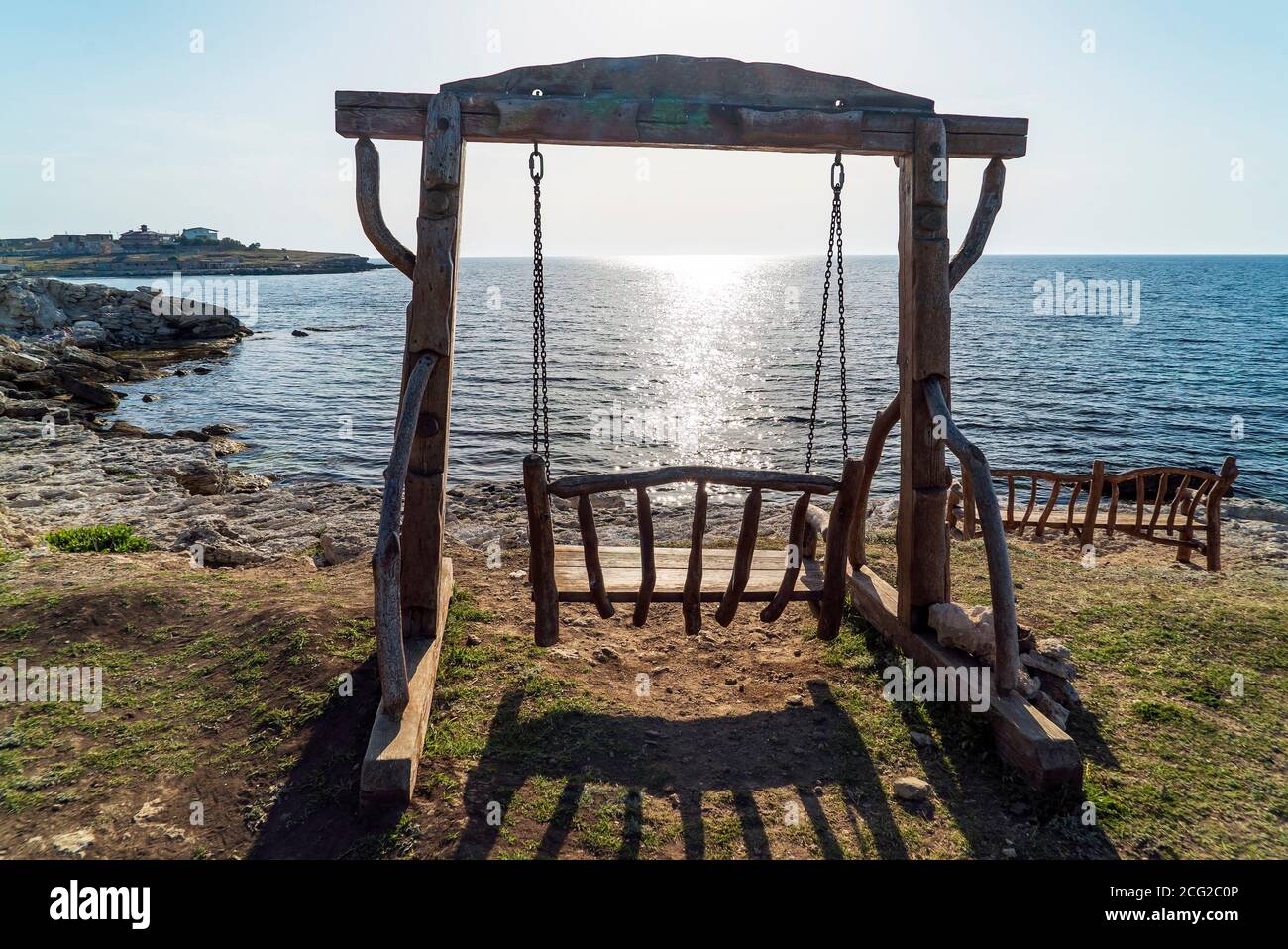 Wooden swing on the beach in the rays of the setting sun Stock Photo