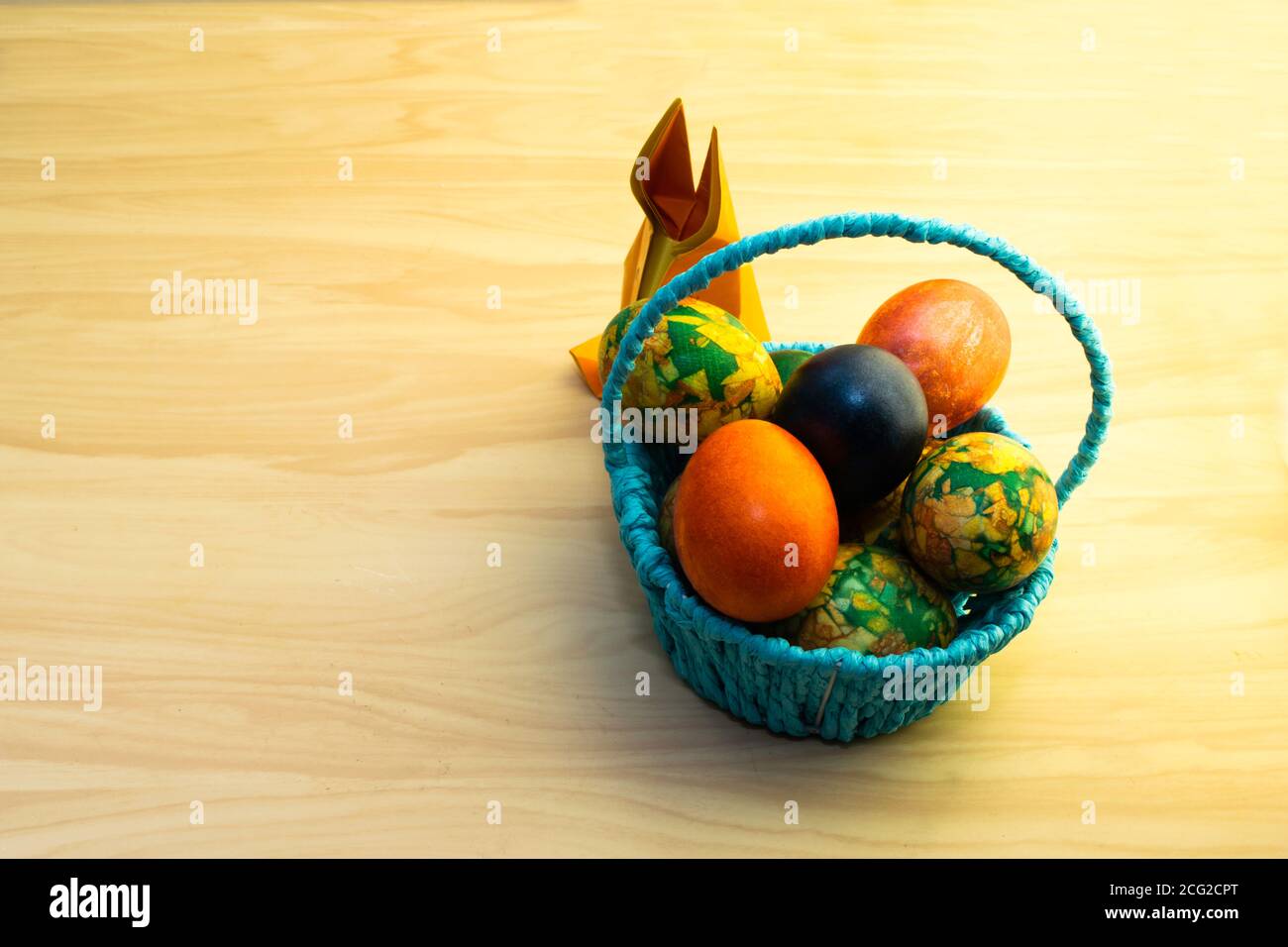 Easter eggs lying in the blue basket and a paper rabbit on a yellow ...