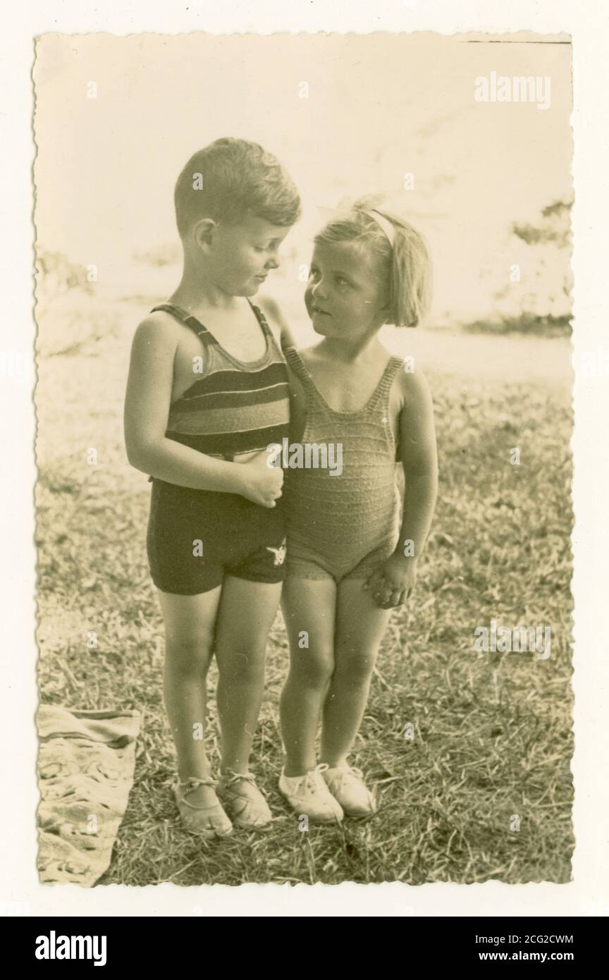 WW2 era photograph of cute young children on holidays, boy and girl, possibly siblings, wearing woollen swimsuits, canvas shoes,  circa 1930 1940, U.K. Stock Photo