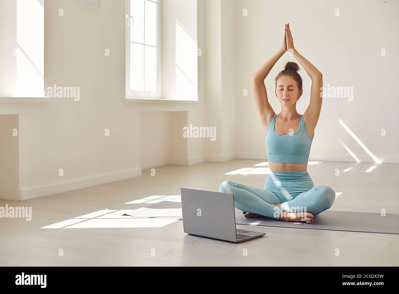 Female yoga coach showing asana in front of laptop during online video ...