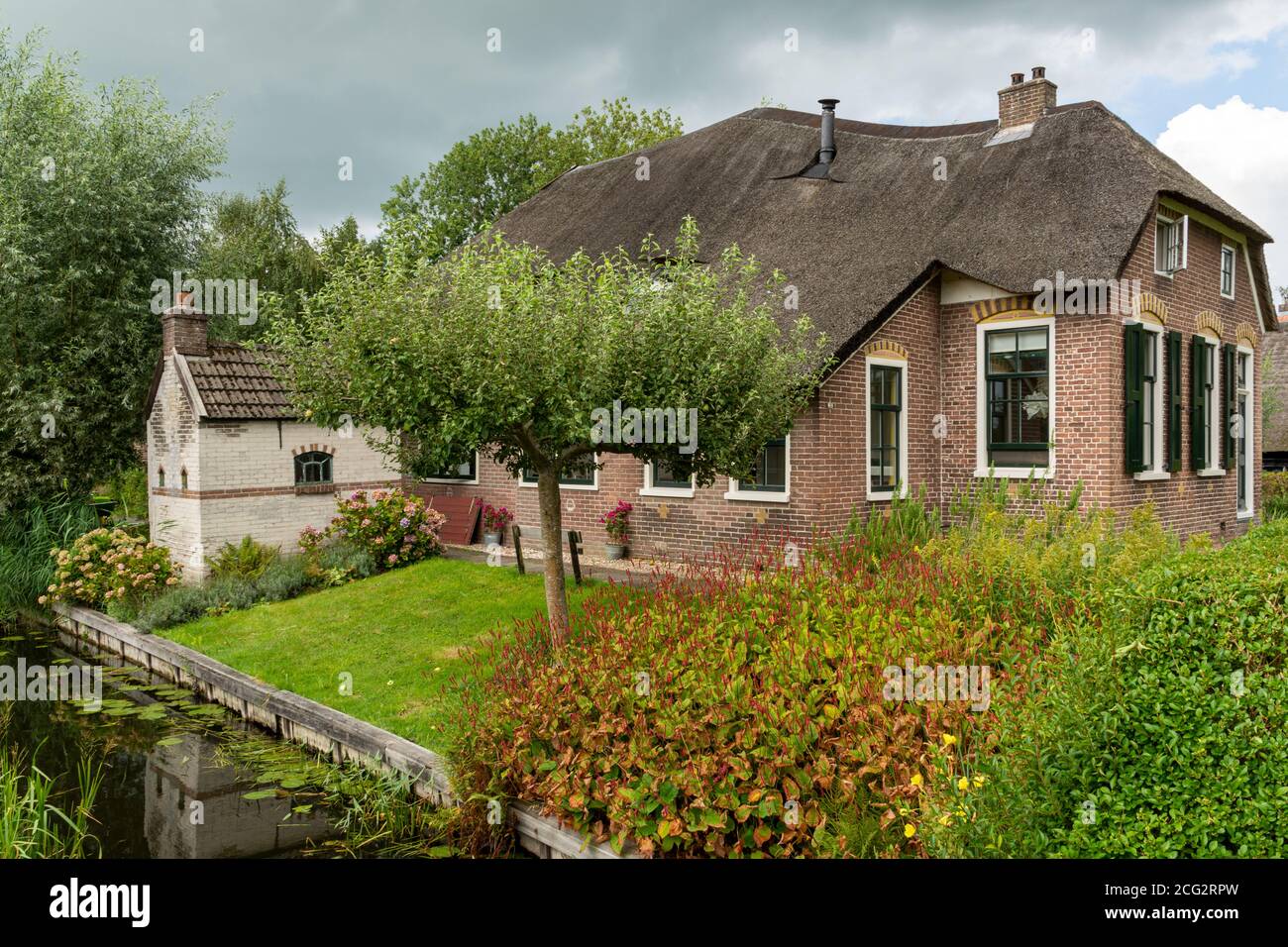 Giethoorn, The Netherlands - August 28, 2020: House with thatched roof at a small canal Stock Photo