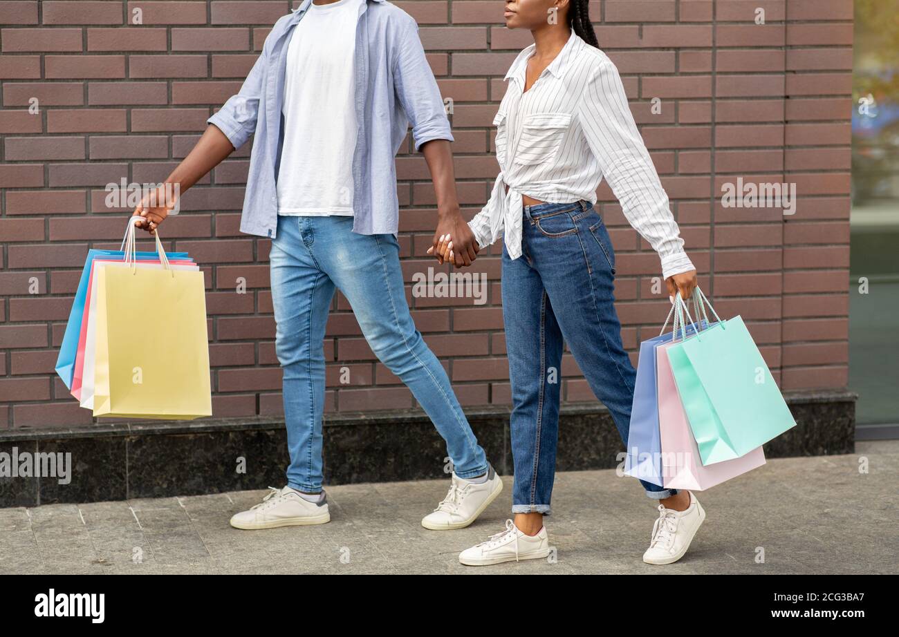 Shopping in mall on weekends. African american couple with multicolored bags Stock Photo