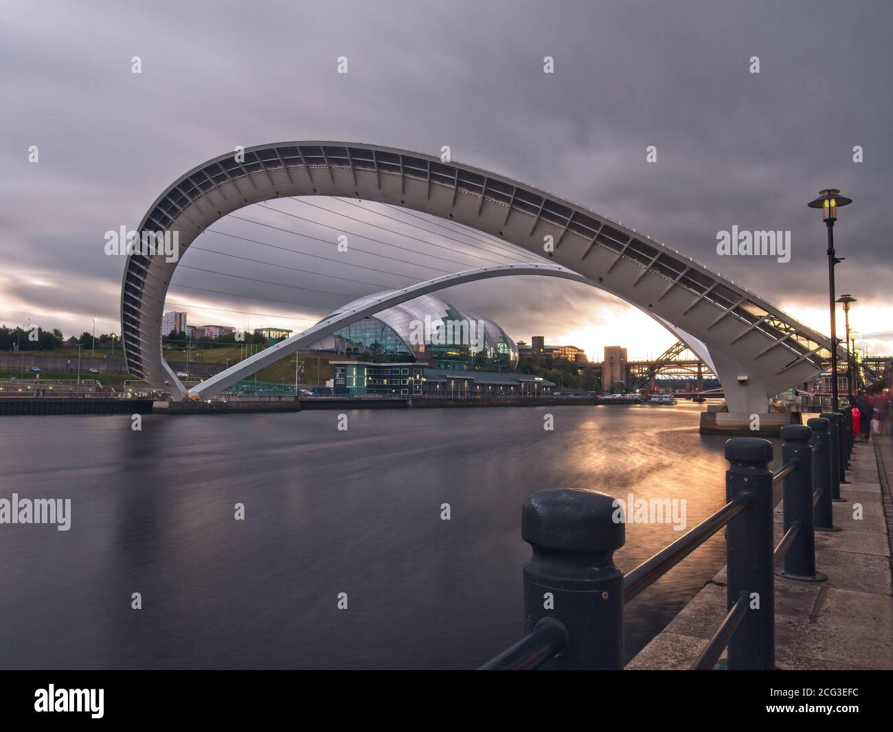The Gateshead Millenniumm Bridge spanning the River Tyne captured in its tilted position at dusk from Newcastle quayside. Stock Photo