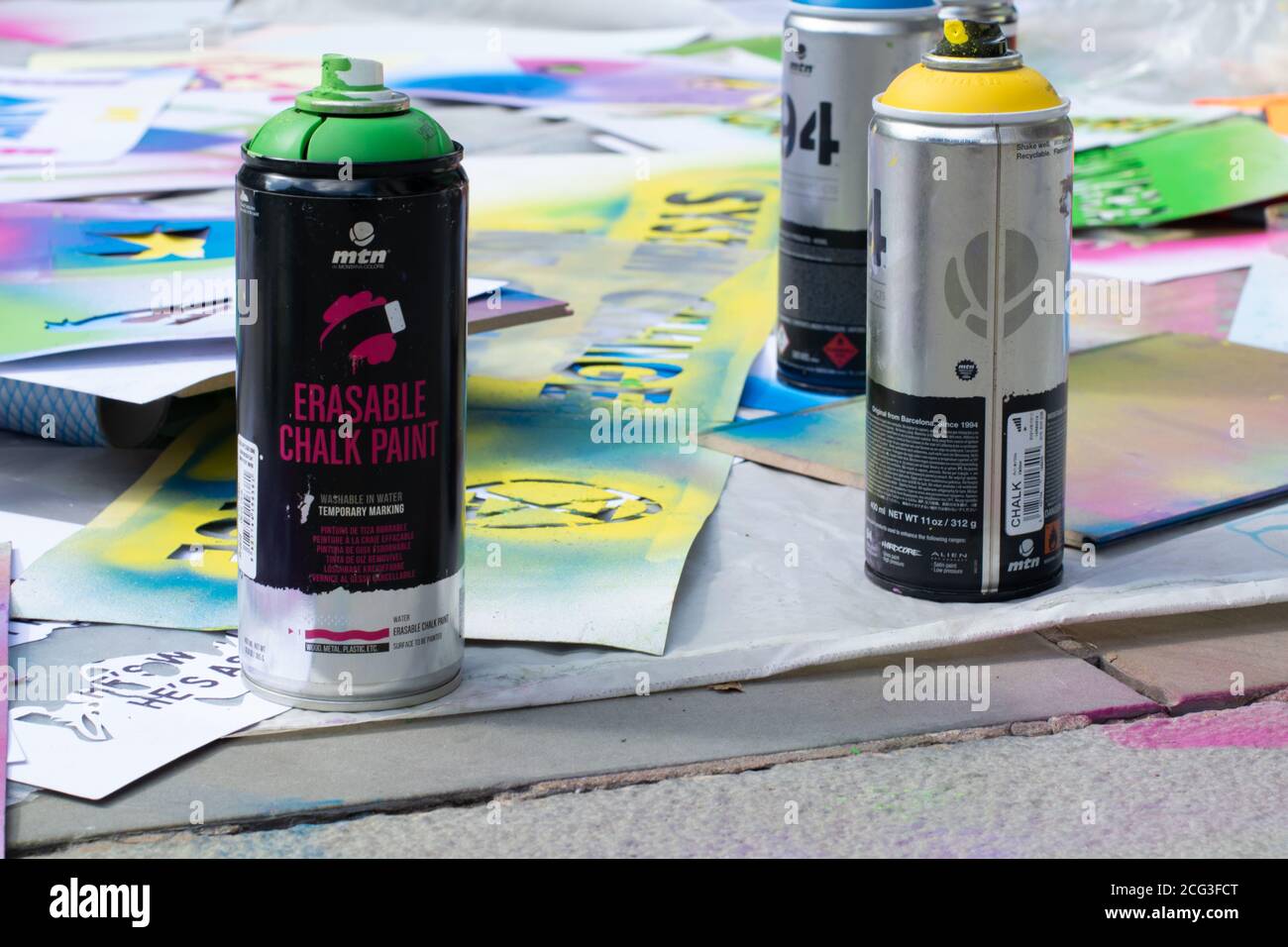 Stencil spraying using Montana Colors erasable chalk paint. Three cans of spray paint. Extinction Rebellion protest Manchester, UK with symbol. Stock Photo