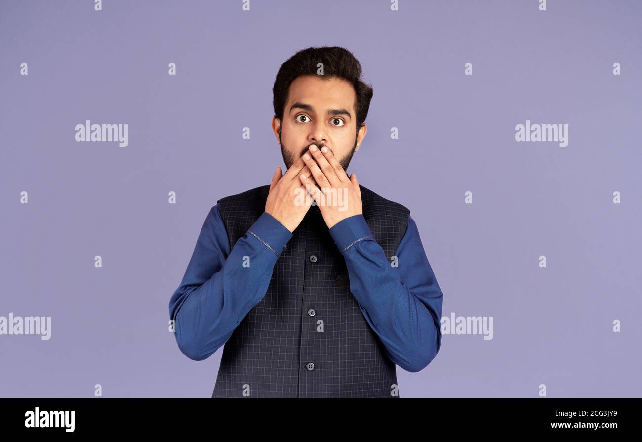 No way. Indian man covering mouth with hand in shock over violet background Stock Photo