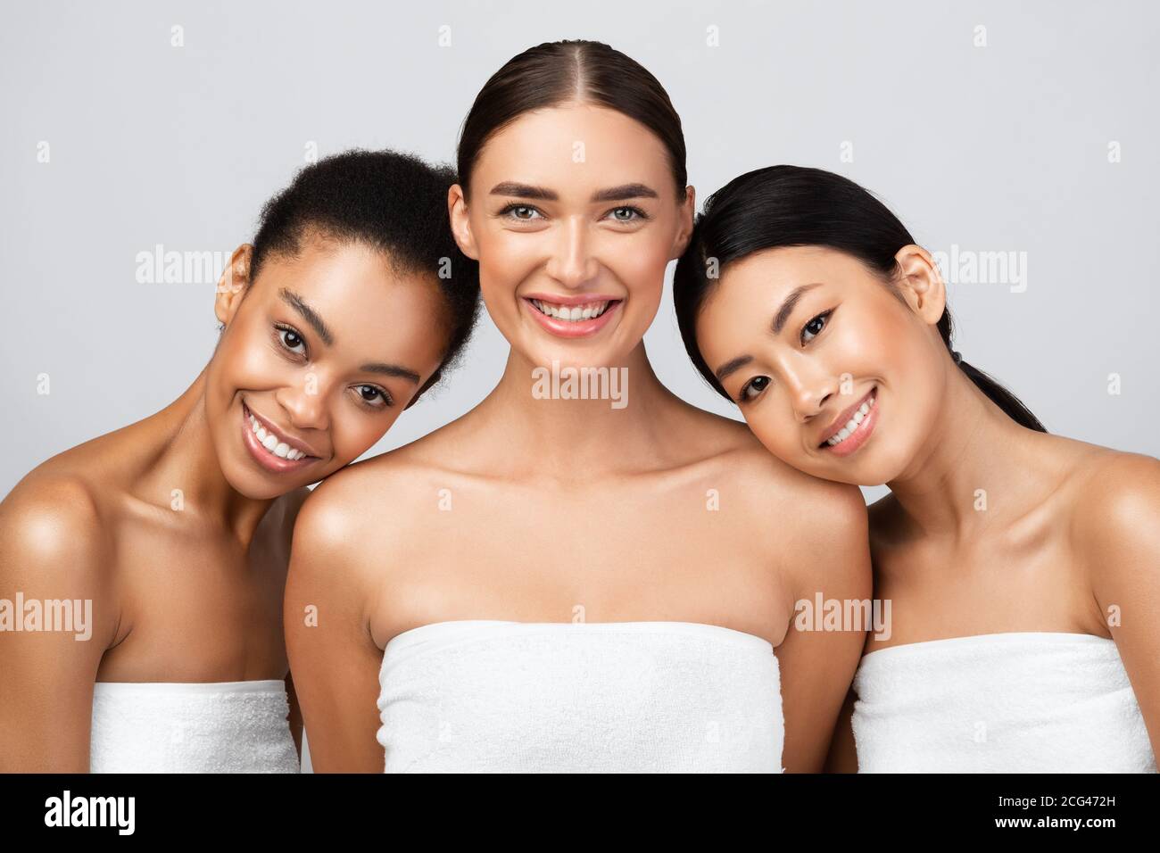 Girls Wrapped In Towels Standing On Gray Background After Shower Stock Photo
