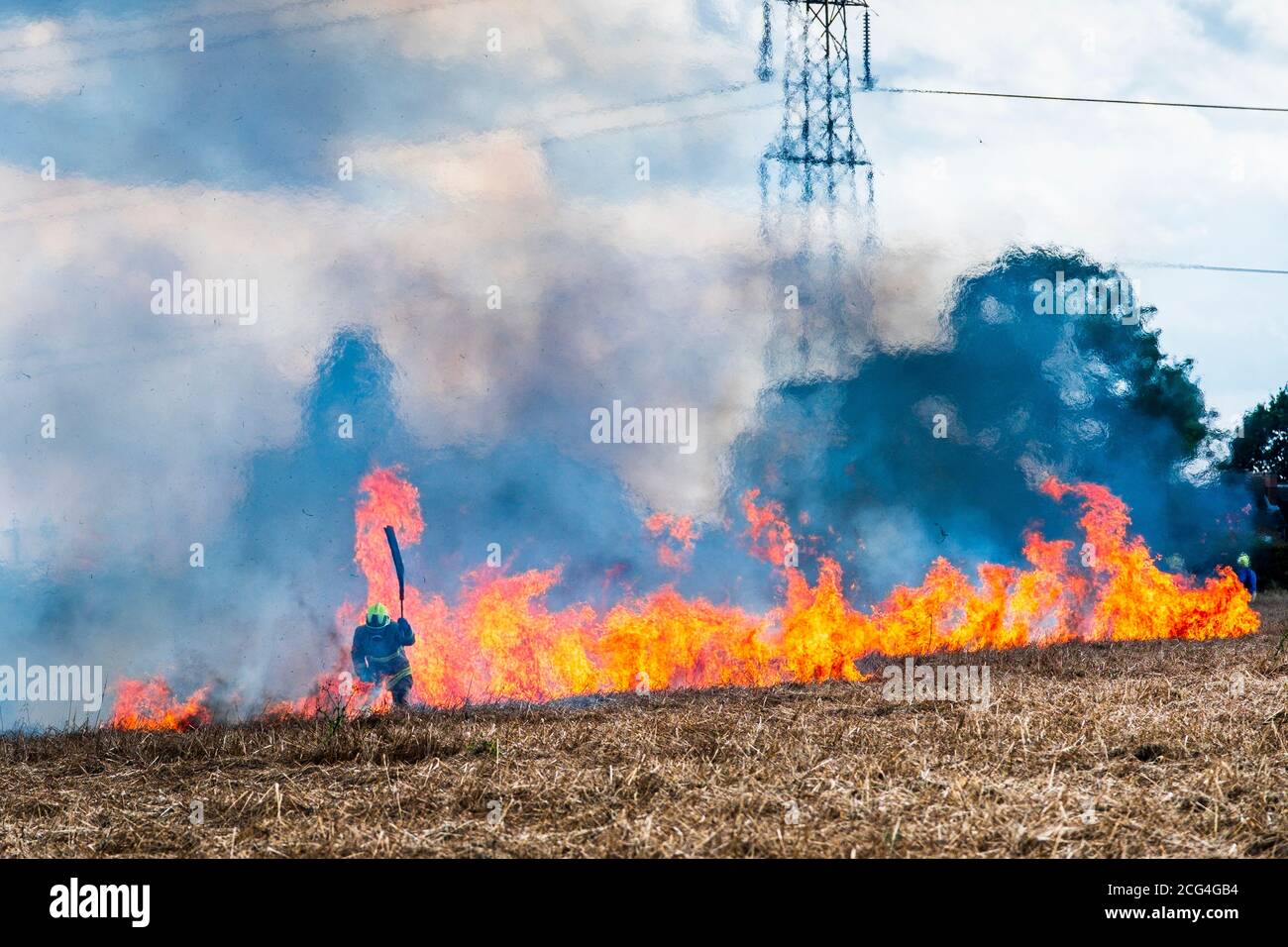 Firemen in breathing gear battle a crop fire believed to have been started deliberately. Stock Photo