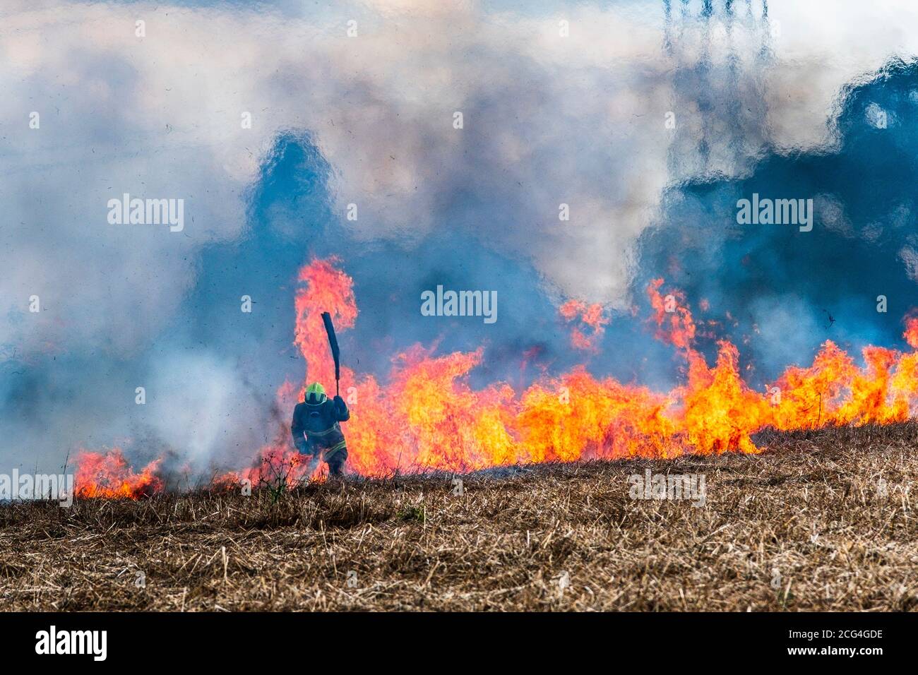 Firemen in breathing gear battle a crop fire believed to have been started deliberately. Stock Photo