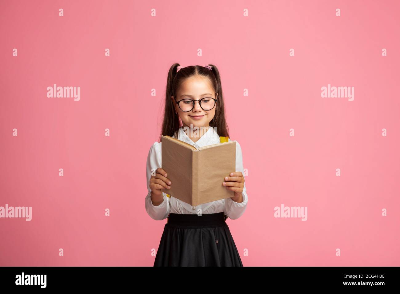 Lifestyle and spare time. Happy schoolgirl with glasses reads book Stock Photo