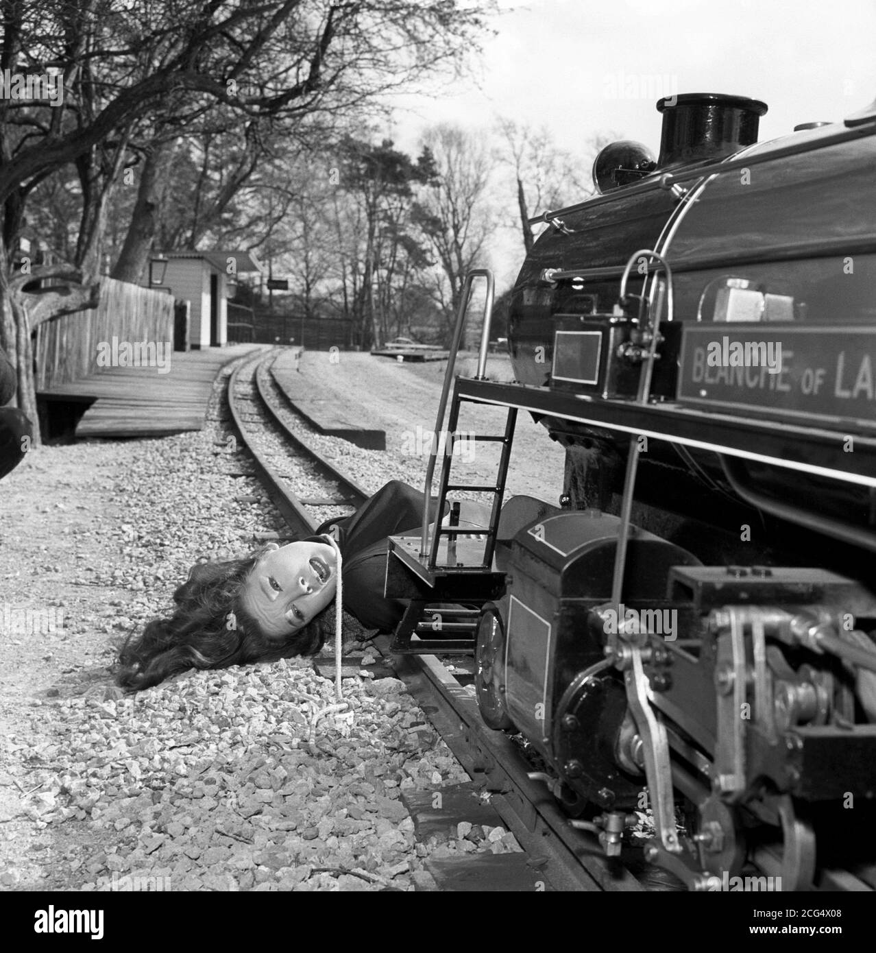 Actress Diana Rigg on location for a new series of the television action series 'The Avengers'. In this shot, she is tied to the rails of a miniature railway on Lord Gretton's Stapleford Park estate, near Melton Mowbray, Leicestershire, for the episode 'The Gravediggers'. Stock Photo