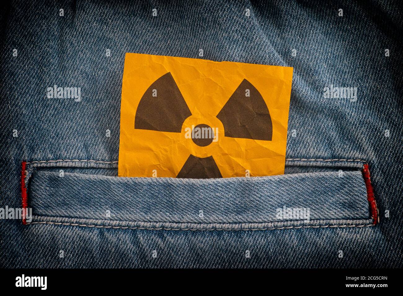 Radiation warning sign sticking out from a jeans pocket. Close up. Stock Photo