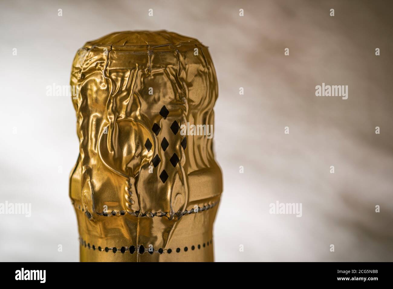 Close up of unopened bottle of champagne top, gold foil intact. Stock Photo