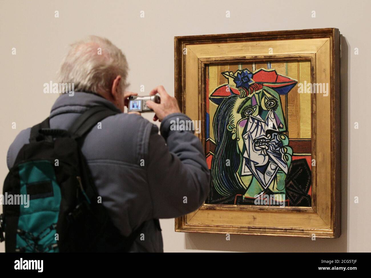 A visitor takes a photograph Weeping Woman (1937), by Pablo Picasso, on display during a press preview of the 'Picasso and Modern British Art' exhibition, at Tate Britain in London. Stock Photo