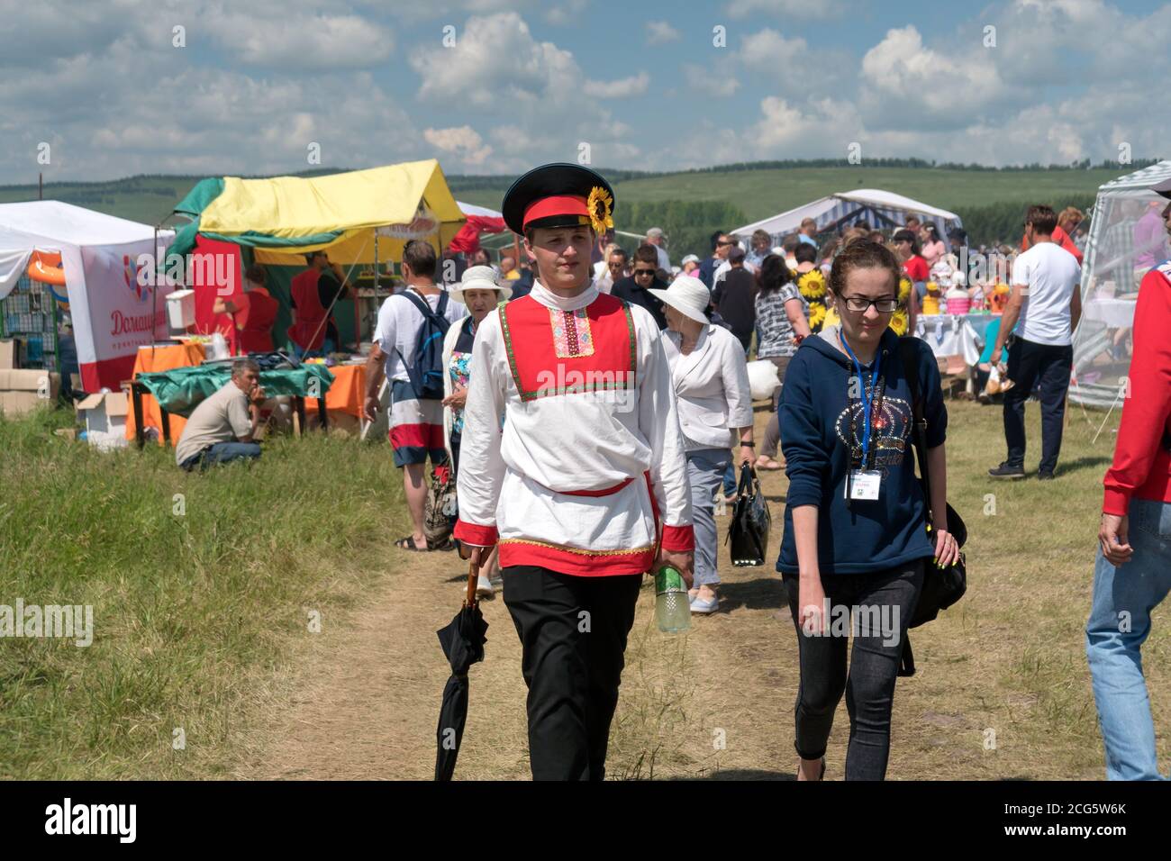A man in Russian folk costume walking down the fair street during the ethnic festival Karatag on the shore of a Large lake. Stock Photo