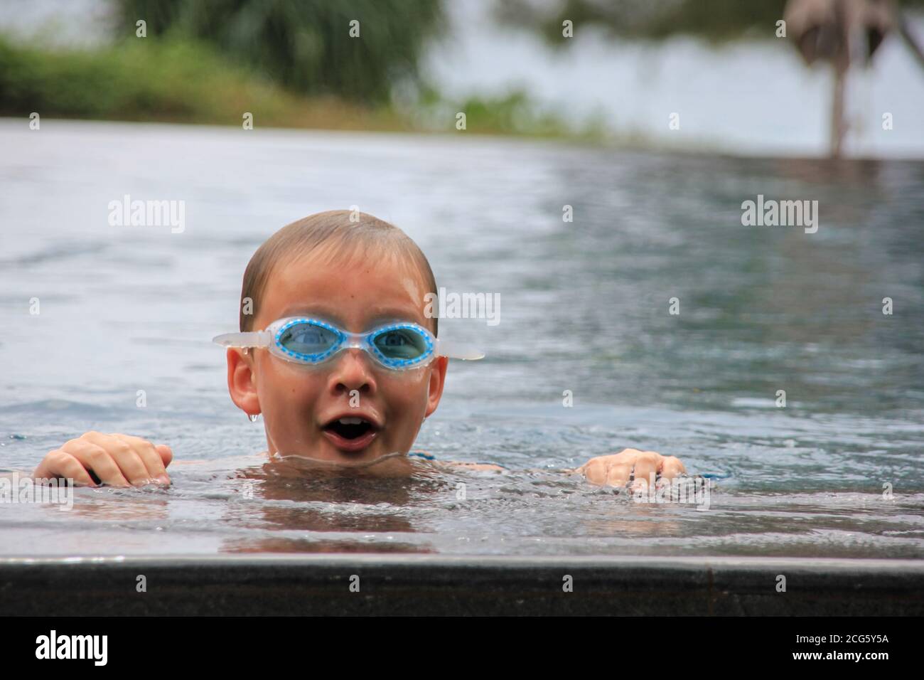 Portrait of happy eight year old boy having fun in swimming infinity