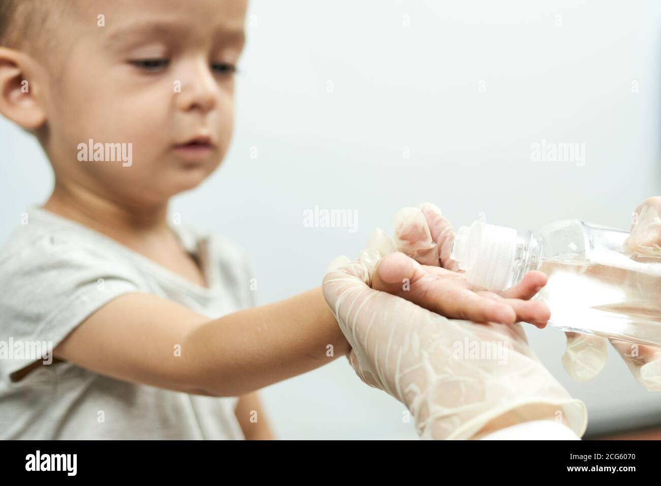 Doctor putting hand sanitizer to baby hands. Teaching a baby boy hand